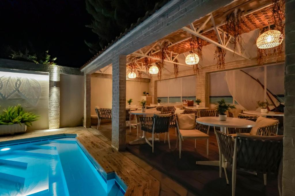 Eleganta terase ar baseinu, kas apgaismota ar mājīgām lampām, radot relaksējošu atmosfēru nakts laikā. Viegli mēbeļu komplekti un zaļumi papildina skaisto vidi.