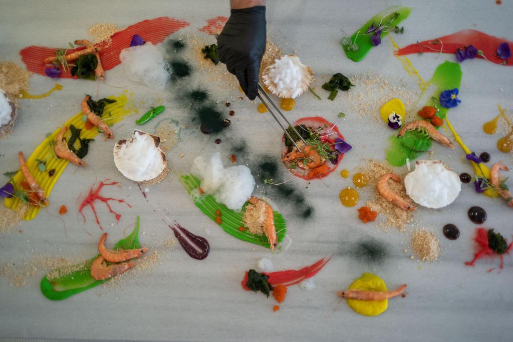 Radoša gastronomijas kompozīcija uz galda ar krāsainiem mērījumiem, garnelēm un augiem, kas izceļ modernās kulinārijas mākslu.