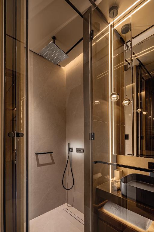 Moderns vannas istabas dizains ar stikla dušas kabīni, akmens sienām un mūsdienīgu apgaismojumu. Eleganta un funkcionāla telpa, kas rada relaksējošu atmosfēru.