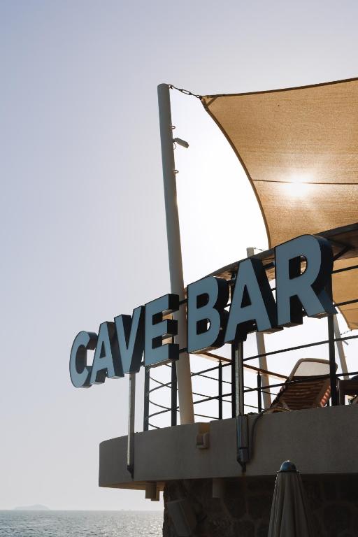 CAVE BAR nosaukums pie jūras, kas redzams zem saules gaismas.