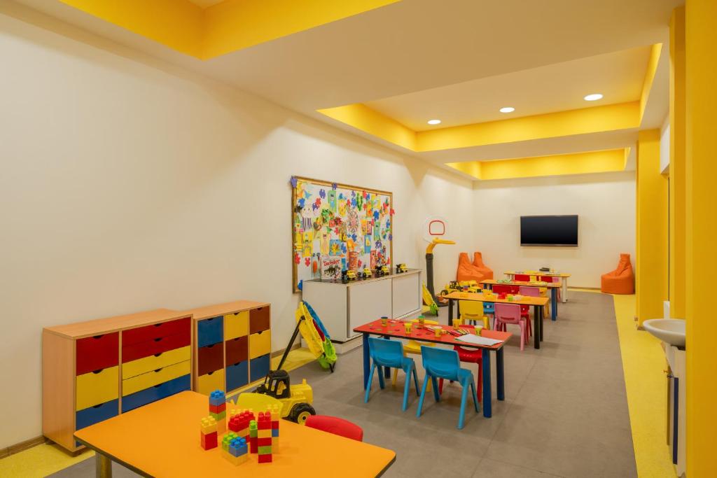 Bērnu spēļu istaba viesnīcā Delphin Diva ar krāsainiem galdiem un rotaļlietām.