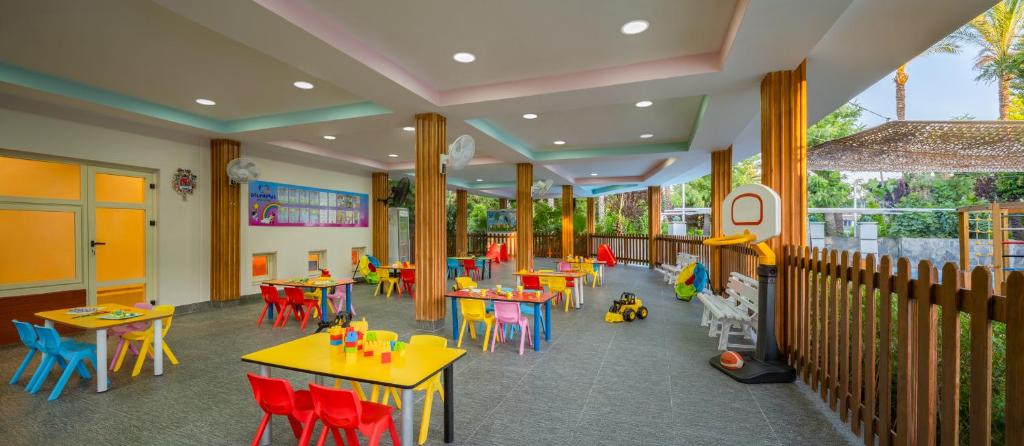 Bērnu rotaļu telpa viesnīcā Delphin Diva ar krāsainiem galdiem un krēsliem.