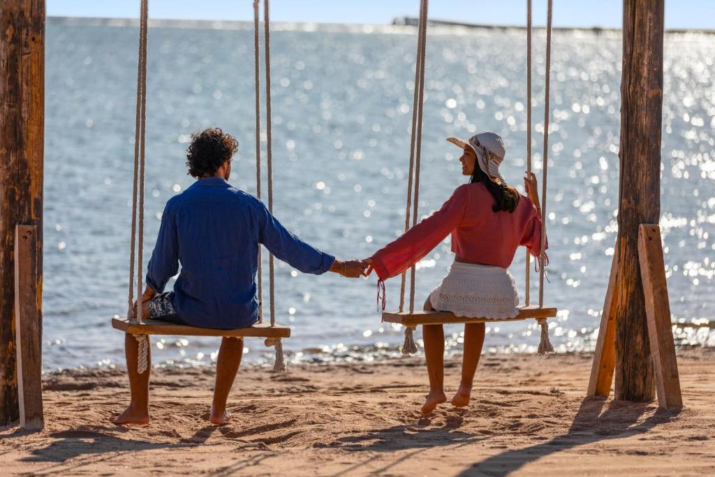 Pāris, kas sēž uz šūpuļtīkla piekrastē, viesnīcā Pickalbatros Royal Albatros Moderna.