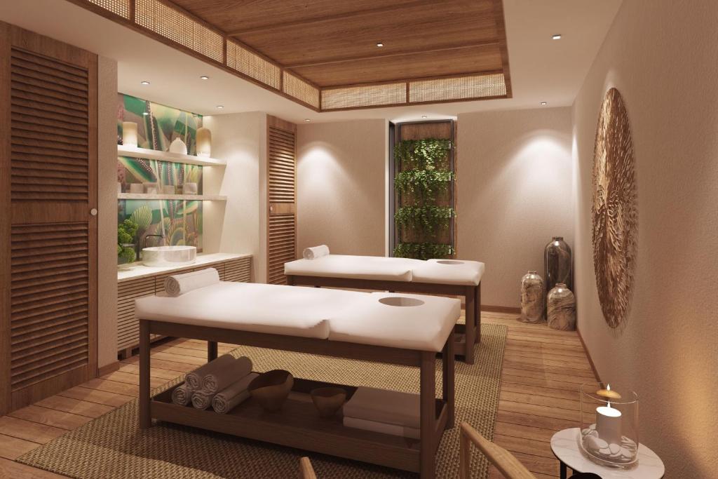 Mūsdienīgs spa interjers ar masāžas galdiem, koka elementiem un relaksējošu augu noformējumu. Telpa radīta mierīgai un atpūtu veicinošai atmosfērai.