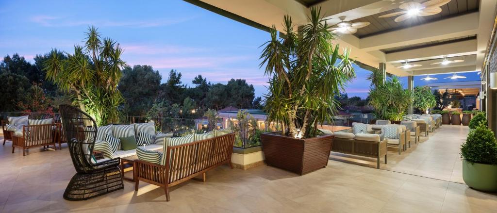 Mūsdienīgs terases laukums pie Ela Excellence Resort Belek ar palmām un komfortablām mēbelēm.