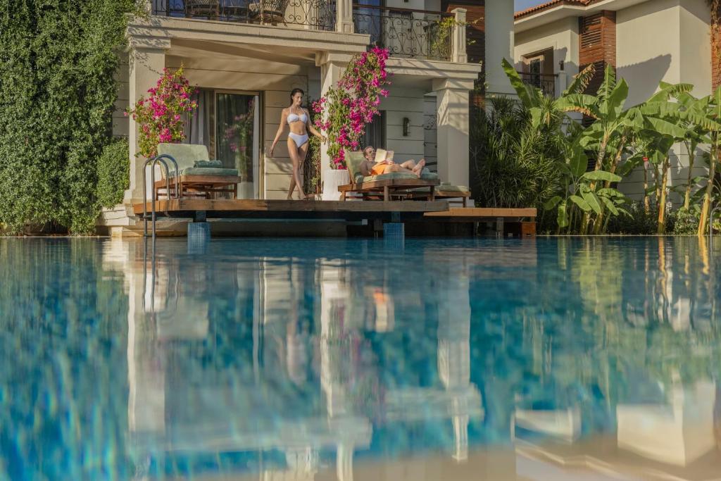 Viesnīcas Ela Excellence Resort Belek baseins ar atpūtas zonu un ziediem.