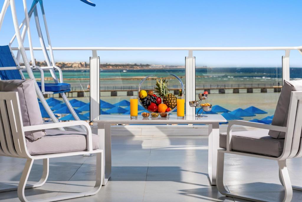 Moderns balkons ar skatu uz jūru, kur uz galda ir augļu plāksne, dzērieni un mājīgas krēsli. Ideāla vieta relaksācijai un atpūtai.