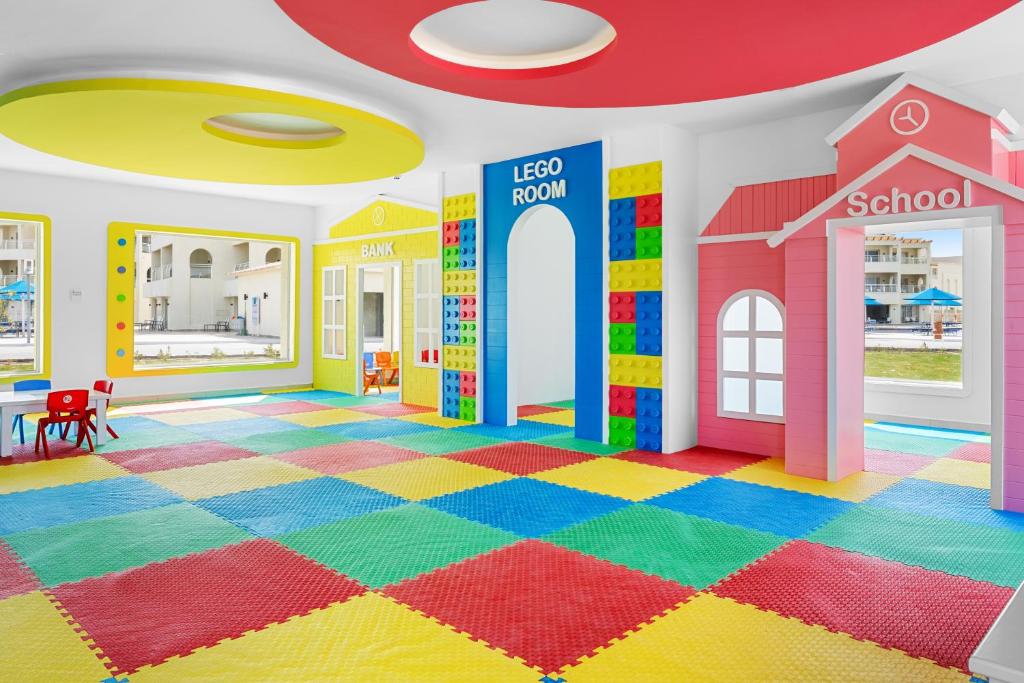 Krāsaina bērnu rotaļu istaba ar LEGO tematu, kurā ir dažādas zonas, piemēram, 