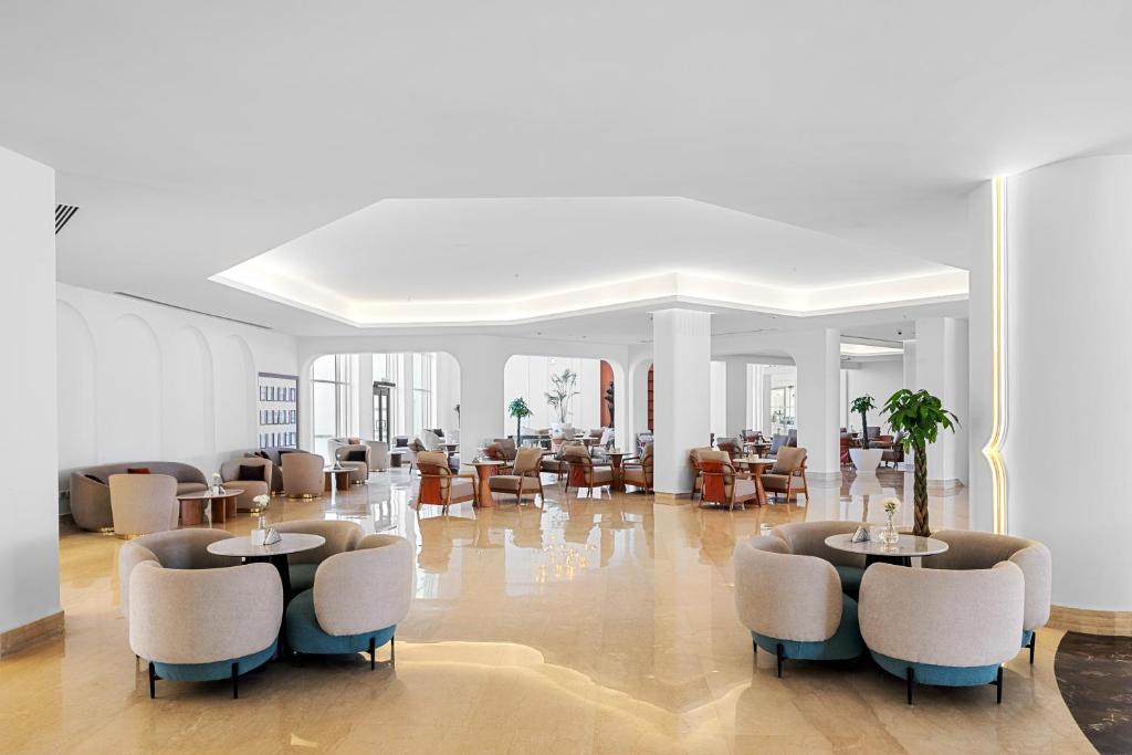 Mūsdienīgs un elegants viesnīcas interjers ar plašu atpūtas zonu, kurā ir komfortabli dīvāni un galdi. Gaismas un apdares elementi rada mierīgu un viesmīlīgu atmosfēru.