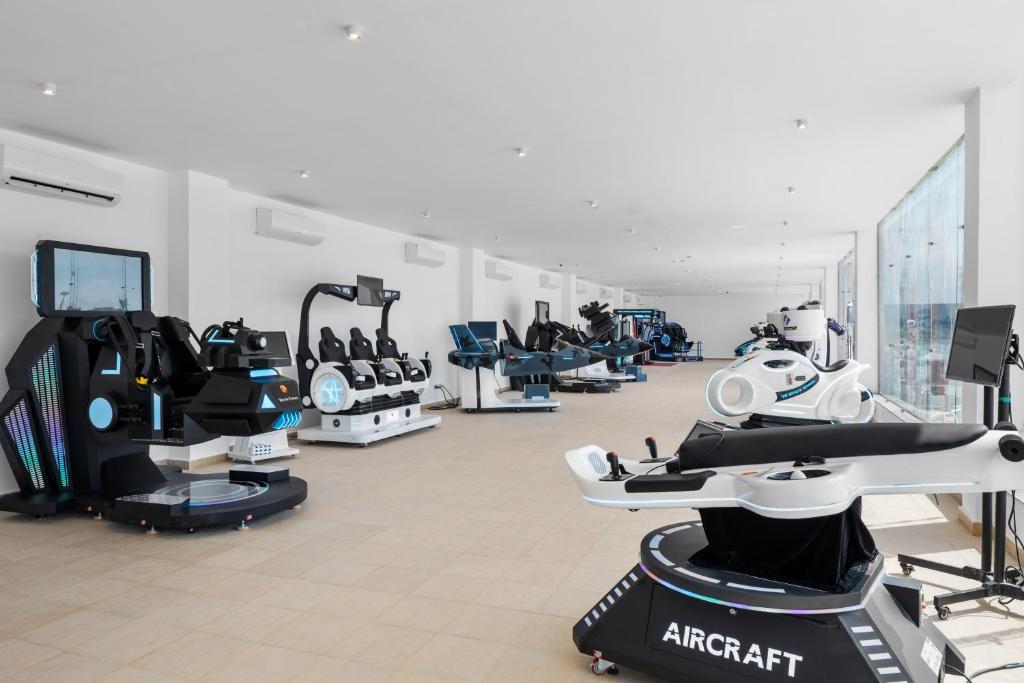 Mūsdienīga izklaides telpa ar dažādiem virtuālās realitātes simulatoriem un spēļu stendiem, kas izkārtoti gaišā un plašā vidē.