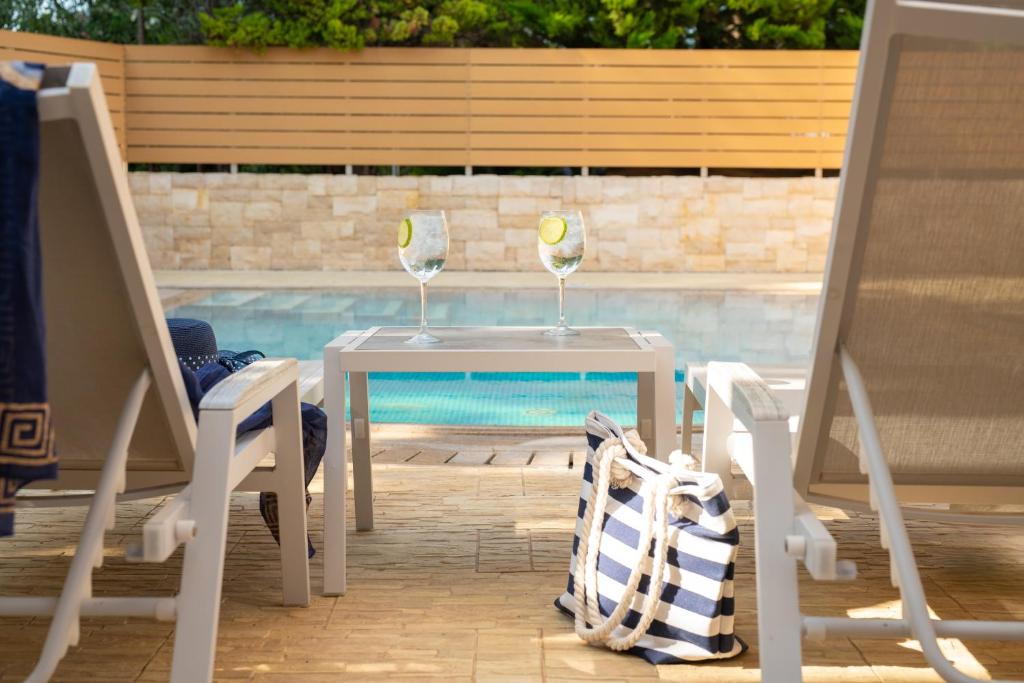 Divas glāzes ar citrona šķēlītēm pie Mitsis Royal Mare baseina.