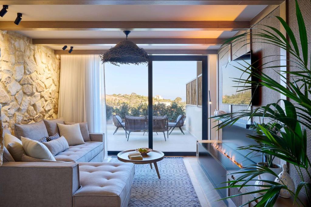 Mūsdienīgs viesnīcas numurs Mirabello Bay Luxury Resort ar akmens sienu un terasi.