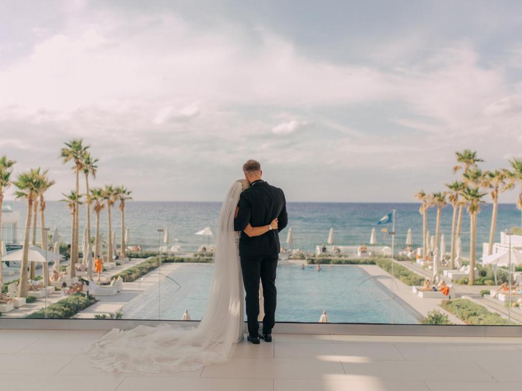 Jaunais pāris pie Grecotel Lux Me White Palace, skats uz jūru un baseinu.