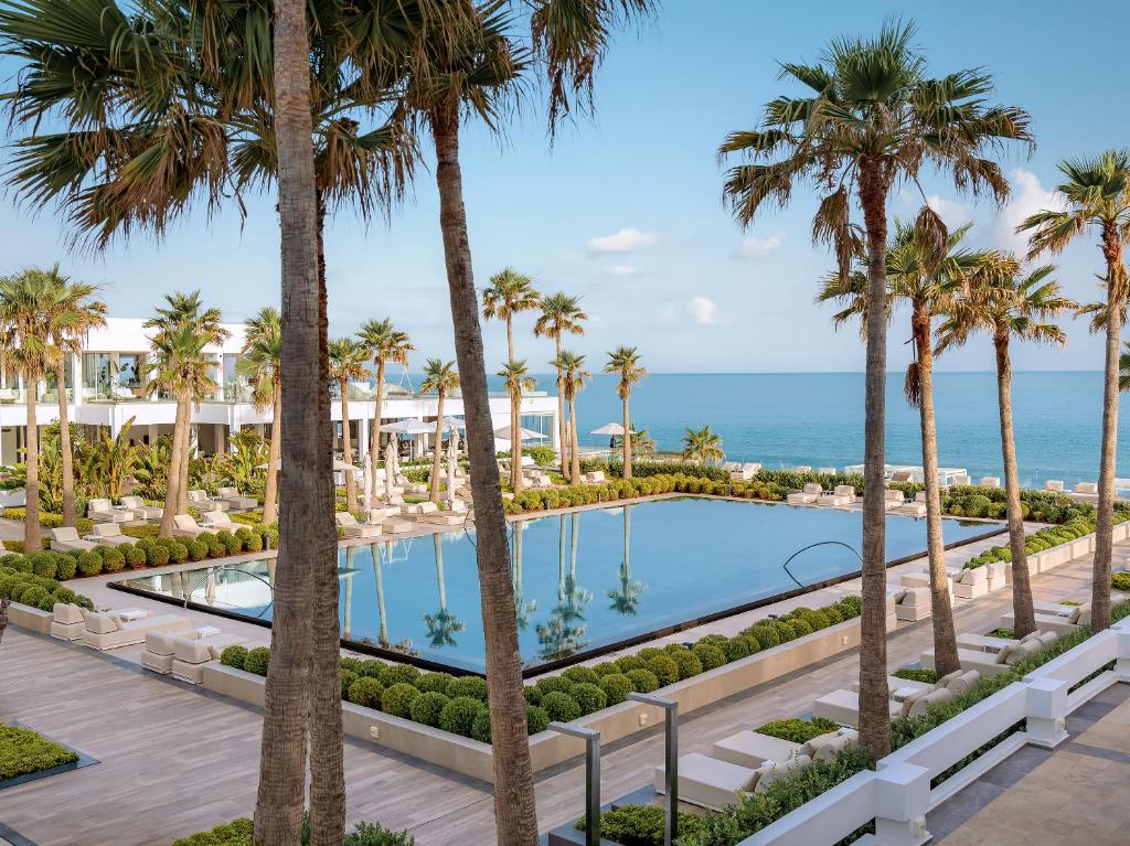 Grecotel Lux Me White Palace viesnīca ar baseinu un palmām piekrastē