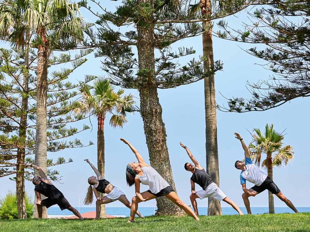 Grupas jogas nodarbība pie Grecotel Lux Me White Palace, zaļā zālienā.