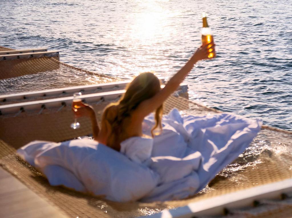 Sieviete ar dzērienu relaksējas pie Grecotel Lux Me White Palace