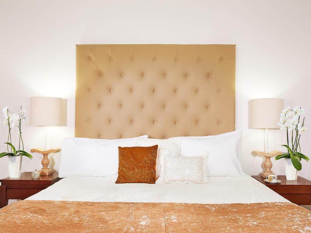 Mājīgs numurs Grecotel Casa Adele ar elegantu gultu un dekoratīvām spilvendrānām.