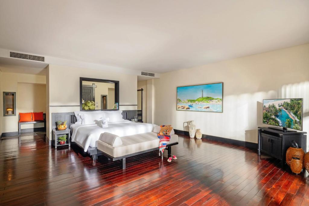 Mūsdienīgs guļamistabas interjers ar lielu gultu, ērtu dīvānu un televizoru, kā arī mākslas darbiem uz sienām. Grīda ir izgatavota no koka, radot siltu un viesmīlīgu atmosfēru.