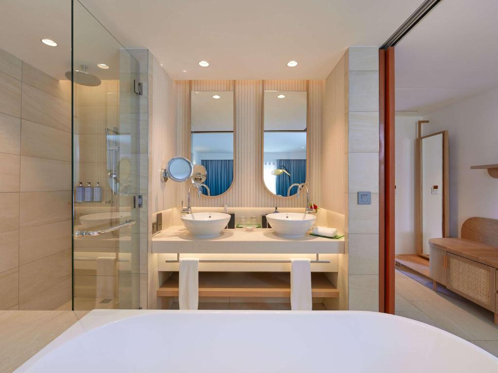 Mūsdienīgs un elegants vannas istabas interjers ar divām izlietnēm, lieliem spoguļiem un stikla dušu, radot komfortablu un stilīgu atmosfēru.