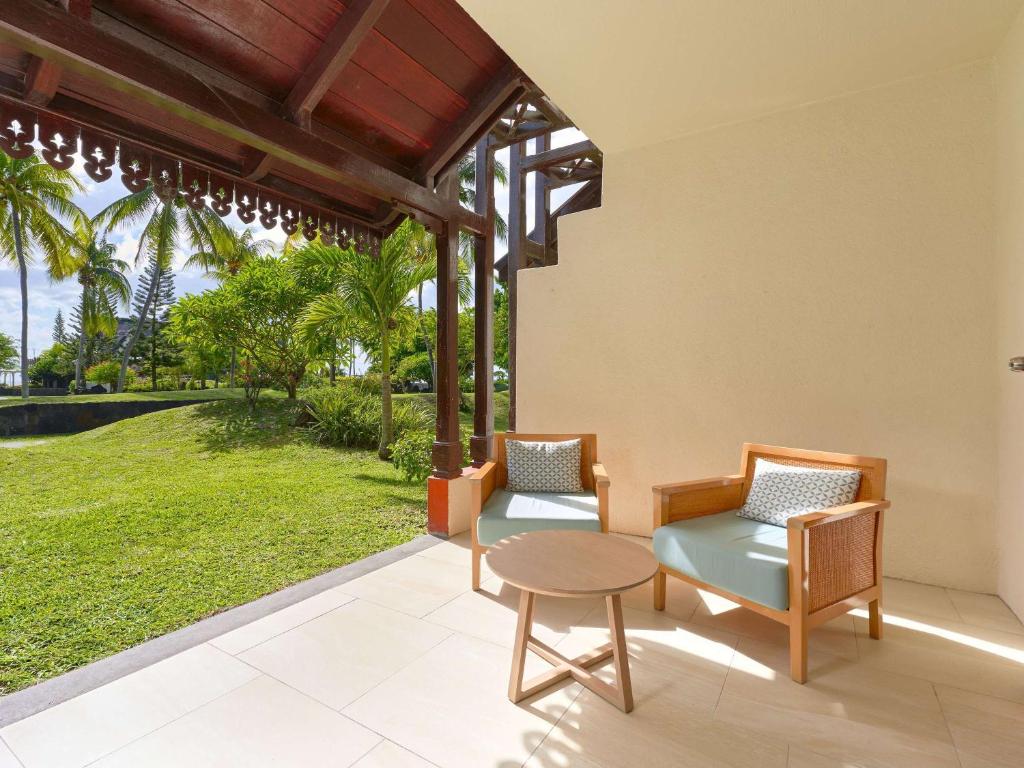 Balkona zona ar divām krēslām un galdiņu, apkārt zaļojoša zāle un palmas. Ideāla vieta atpūtai un relaksācijai.