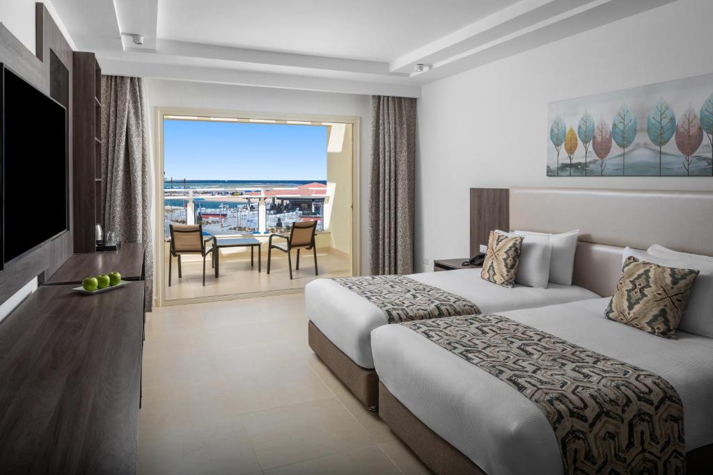 Moderns viesnīcas numurs ar divām gultām, skatu uz ostu un balkonu. Interjerā ir gaiši toņi un mūsdienīgi mēbeļi, radot relaksējošu atmosfēru.