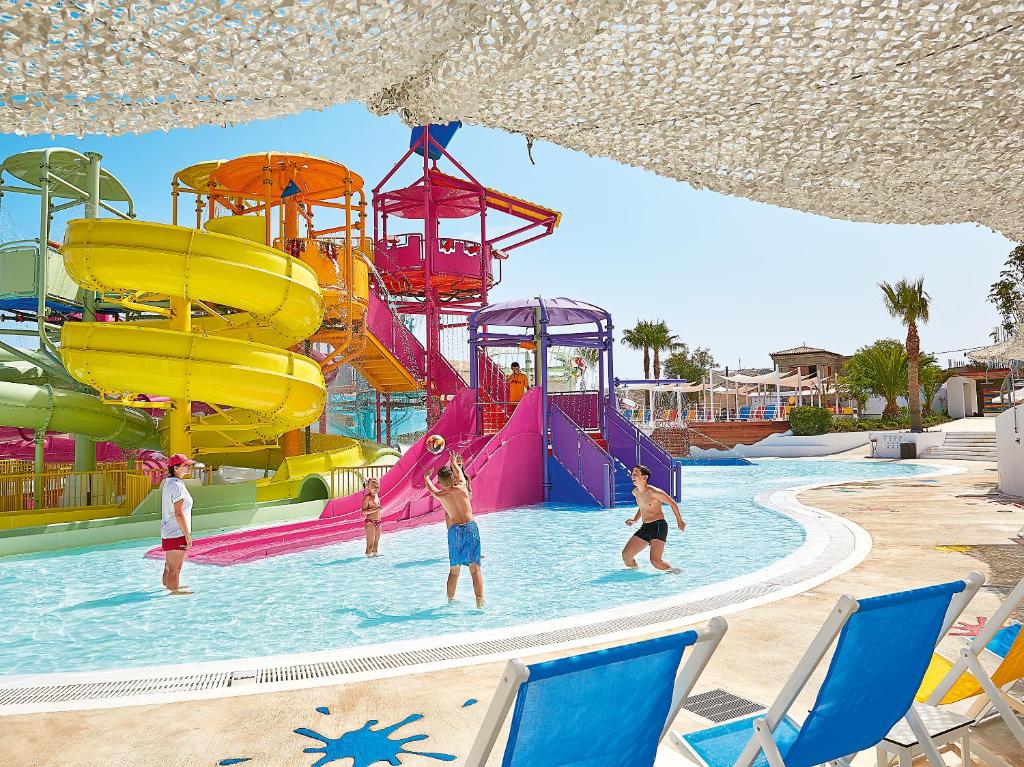 Bērni spēlējas ūdens parkā Grecotel Marine Palace & Aqua Park ar krāsainām slidkalniņiem.