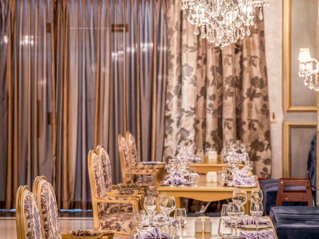 Elegant dining area in Rixos Premium Seagate Sharm with chandeliers and floral curtains.