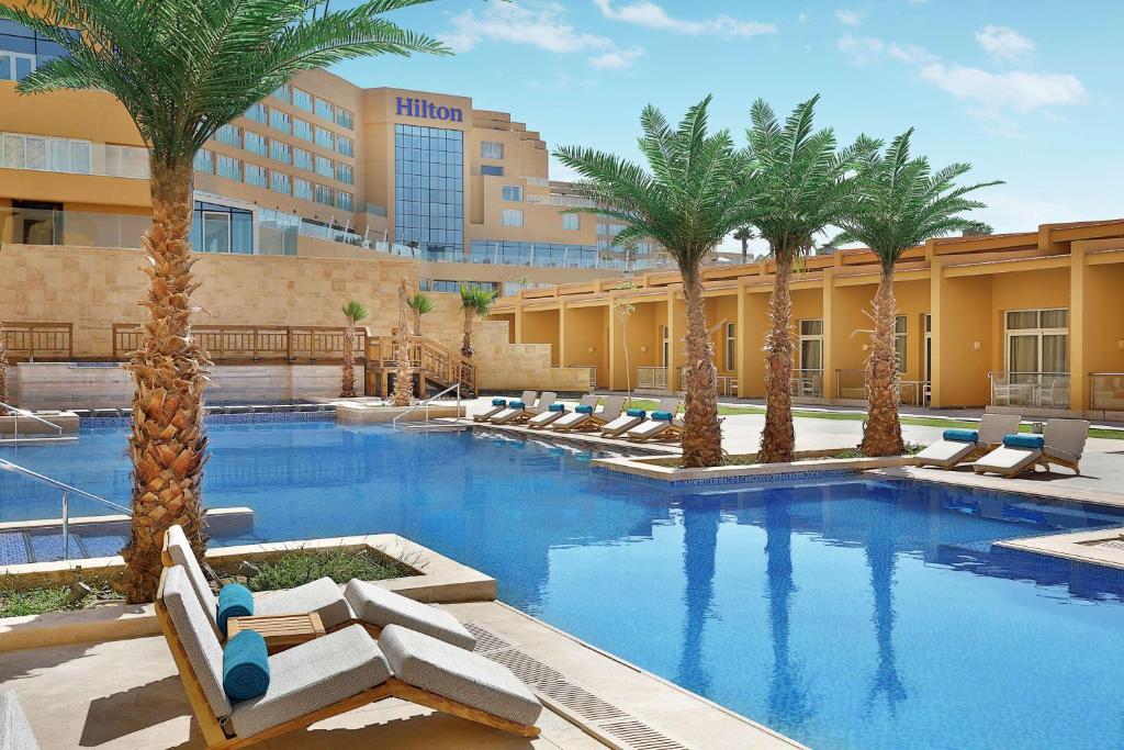 Hilton Hurghada Plaza baseins ar palmām un viesnīcas ēku fonā