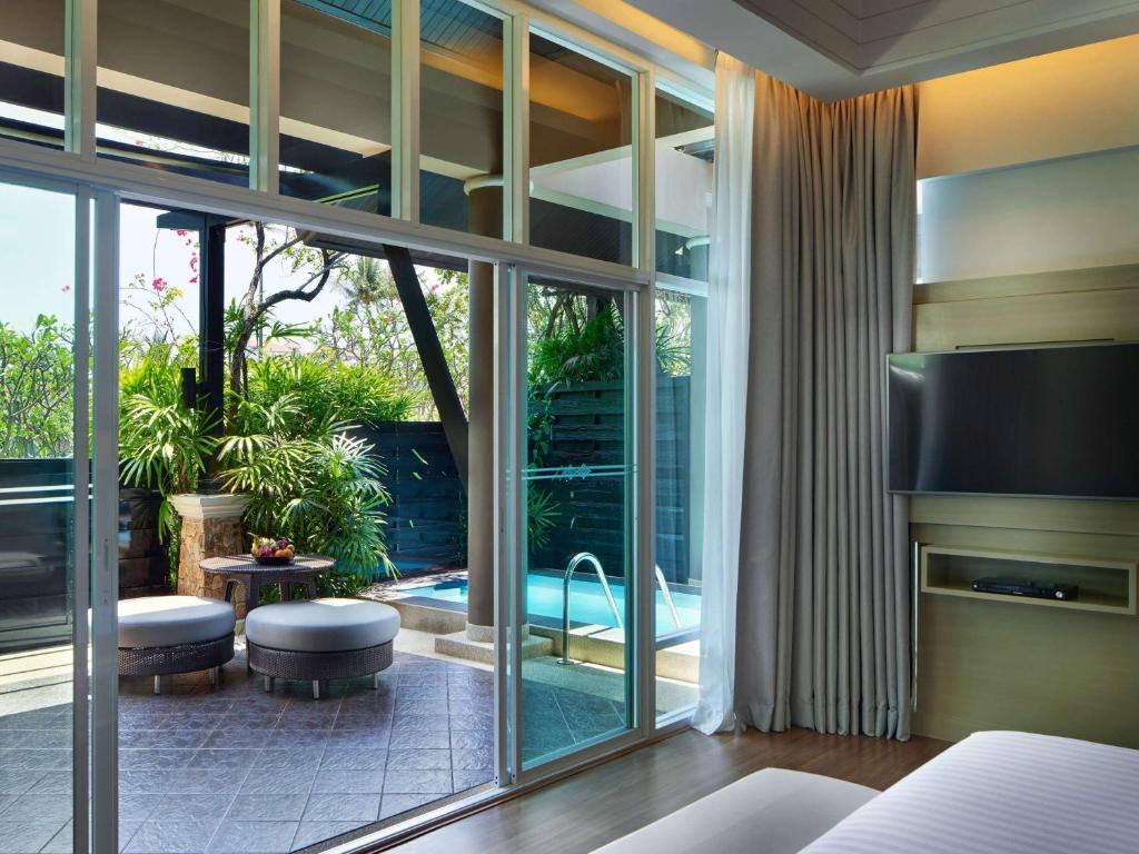 Mūsdienīga viesnīcas numura interjers ar plašu logu, kas vērsts uz privātu terasi ar baseinu un zaļumiem. Ideāla vieta relaksācijai un atpūtai.