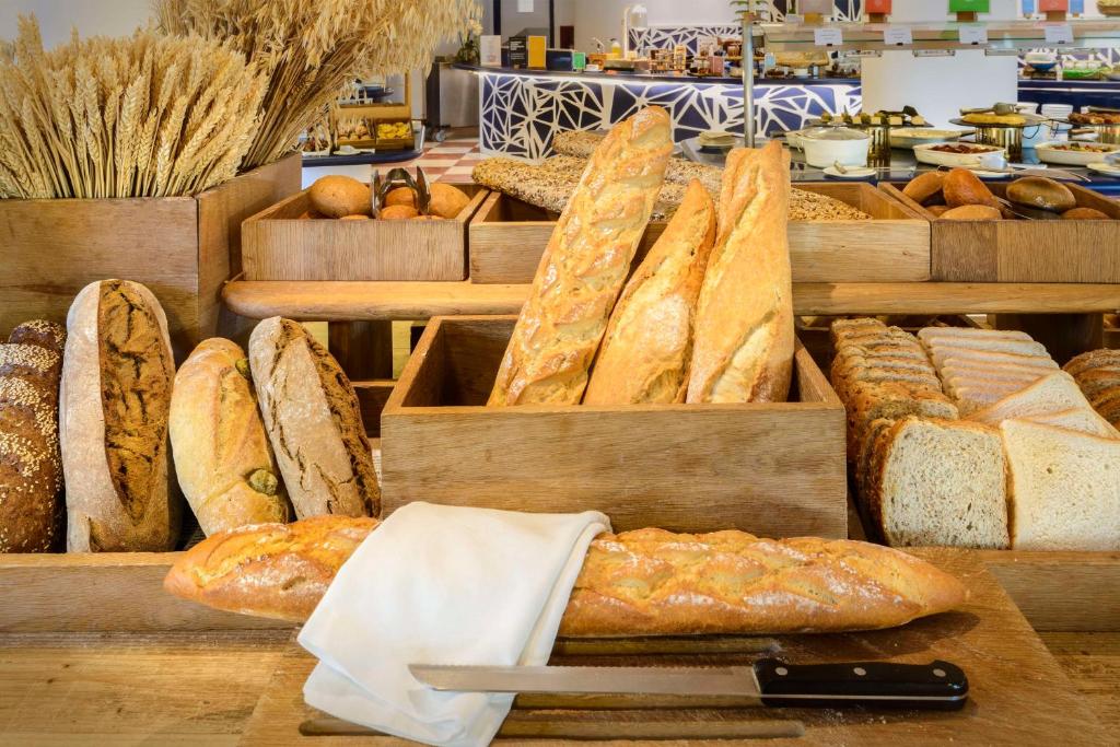 Maizes un graudu izvēle bagātīgā brokastu bufetē, kas piedāvā dažādas maizes šķirnes un dekoratīvus graudus.