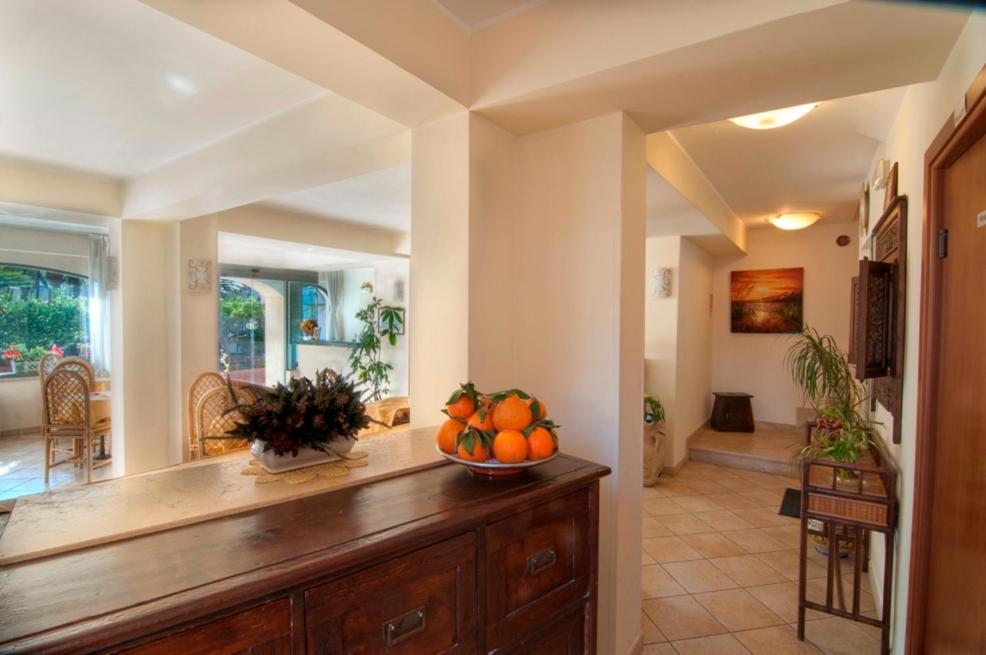 Mūsdienīgs interjers ar gaišu apgaismojumu, koka mēbelēm un dekoratīvām augu kompozīcijām. Skats uz viesistabu ar ērtām krēslām un logiem, kas sniedz dabīgu gaismu.