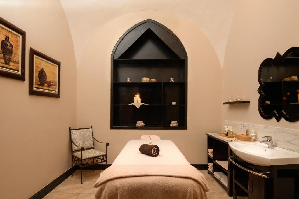 Skaista spa telpa ar relaksējošu atmosfēru, kurā ir masāžas galds, ērta krēsla un dekoratīvi elementi, piemēram, sveces un māksla. Ideāla vieta mierīgai atpūtai un relaksācijai.