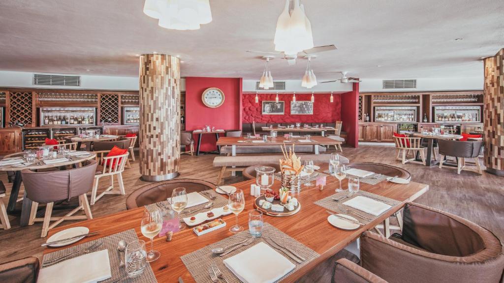 Moderns restorāns ar elegantu interjeru, kurā ir koka akcenti un sarkanas sienas. Galdi ir sakārtoti ar galda piederumiem un dzērieniem, radot aicinošu atmosfēru.