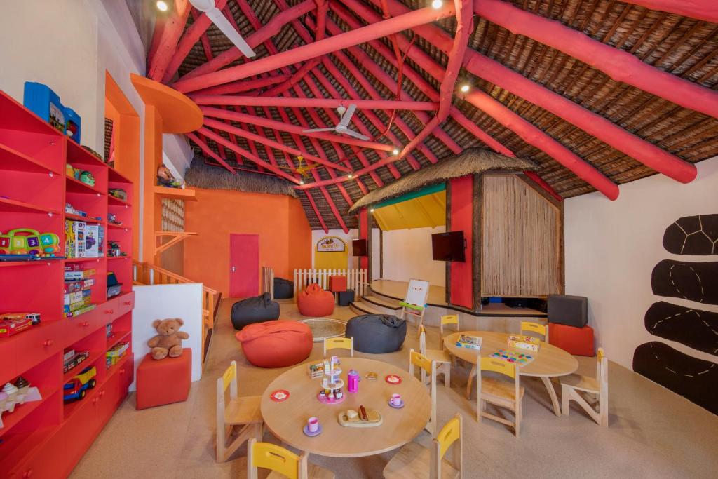 Bērnu spēļu istaba ar krāsainu interjeru, kur ir rotaļlietas, mīkstās sēdvietas un galds aktivitātēm. Telpa piedāvā draudzīgu un radošu vidi bērniem.