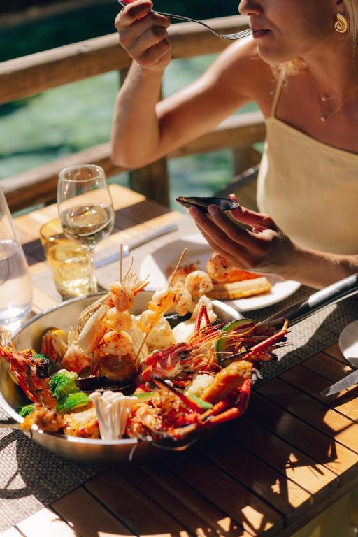 Izsmalcināta jūras velšu maltīte, kurā redzamas garneles un astoņkāji, pasniegta pie pusdienu galda ar dzērieniem. Laimīgs brīdis, baudot gardo ēdienu.