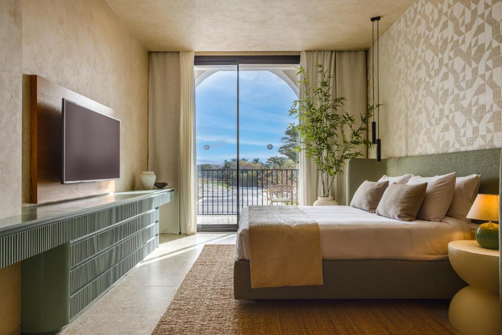 Desert Rose Resort numurs ar skatu uz balkonu un TV.