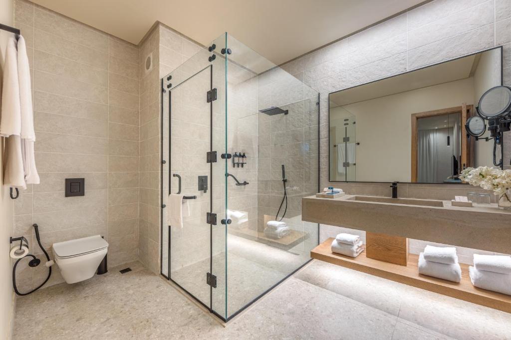 Mūsdienīga vannas istaba Desert Rose Resort ar dušu un lielu spoguli.