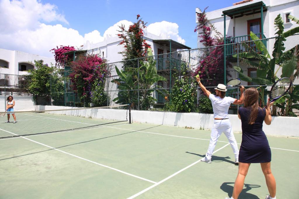 Tennisa spēle pie Parkım Ayaz Hotel, ziedošas krūmu ainavas fonā.