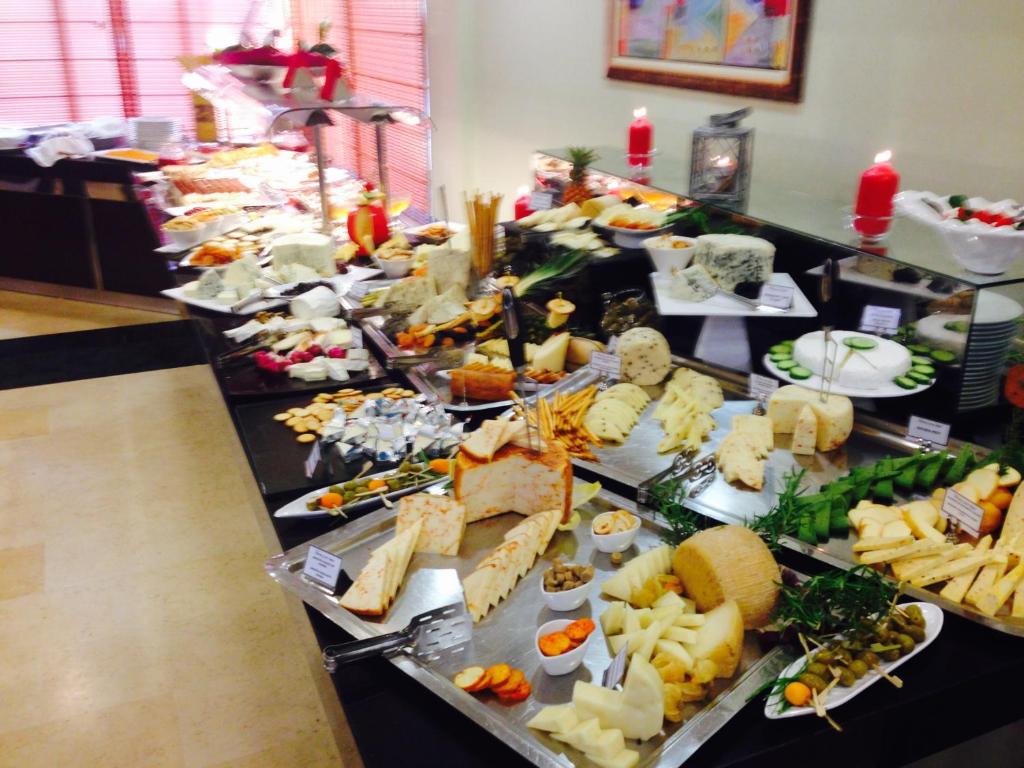 Siera bufete ar dažādu veidu sieriem, augļiem un dārzeņiem, dekorēta ar zaļumiem un svecēm. Ideāli piemērota svinībām un kulinārajām izstādēm.