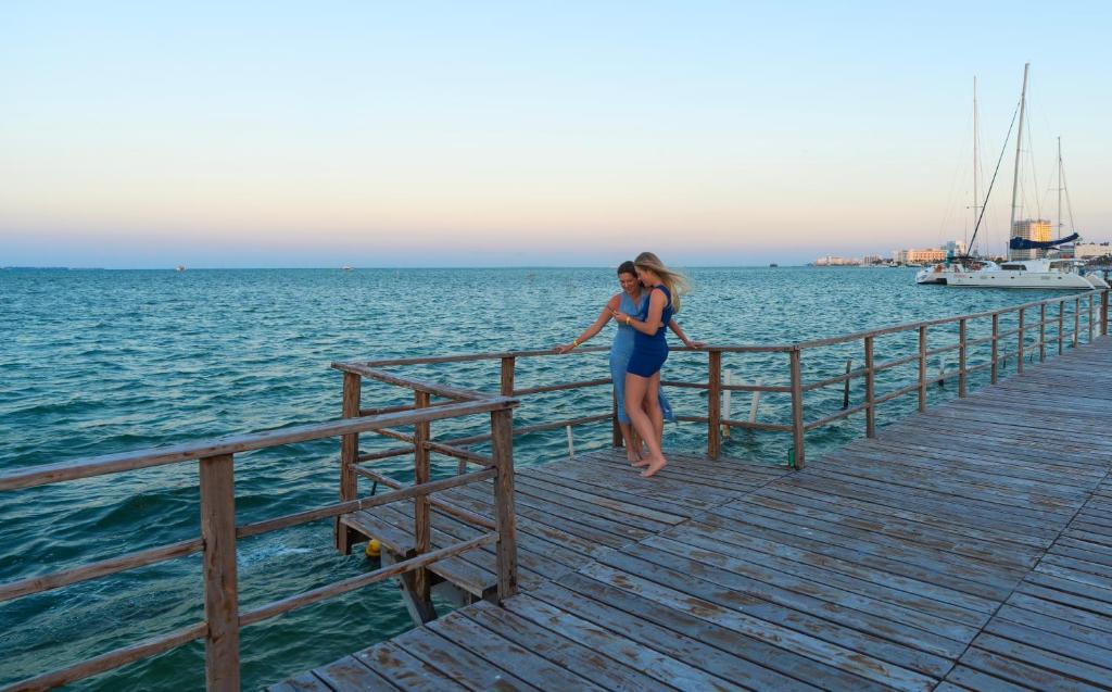 Divi cilvēki, kas bauda saulrietu pie Cancun Bay Resort piestātnes.