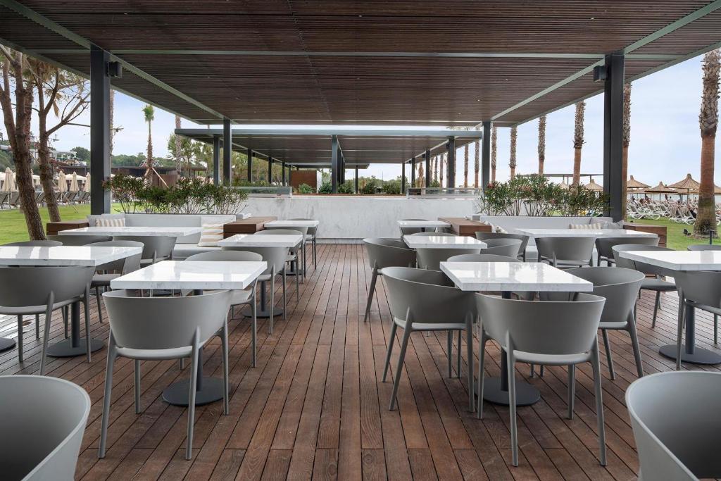 Terases zona ar modernām galdiem un krēsliem pie Voyage Belek Golf & Spa.