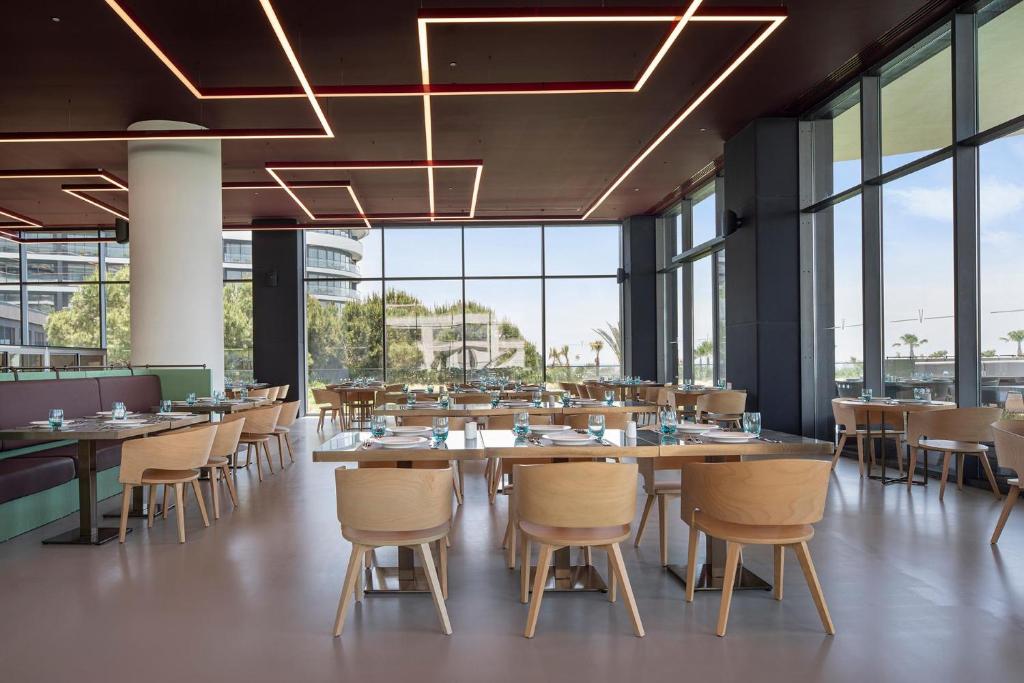 Mūsdienīgs restorāns ar lieliem logiem un elegantiem galdiem pie Voyage Belek Golf & Spa.