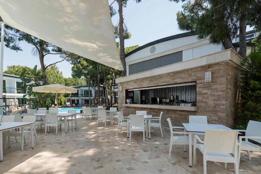 Viesnīcas Voyage Belek Golf & Spa terase pie baseina ar baltām galdiem un krēsliem.