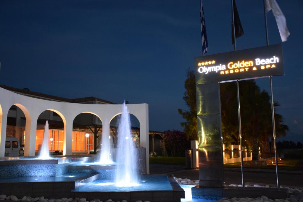 Nakts skats uz Olympia Golden Beach Resort & Spa ar izgaismotiem strūklakām un modernu arhitektūru.