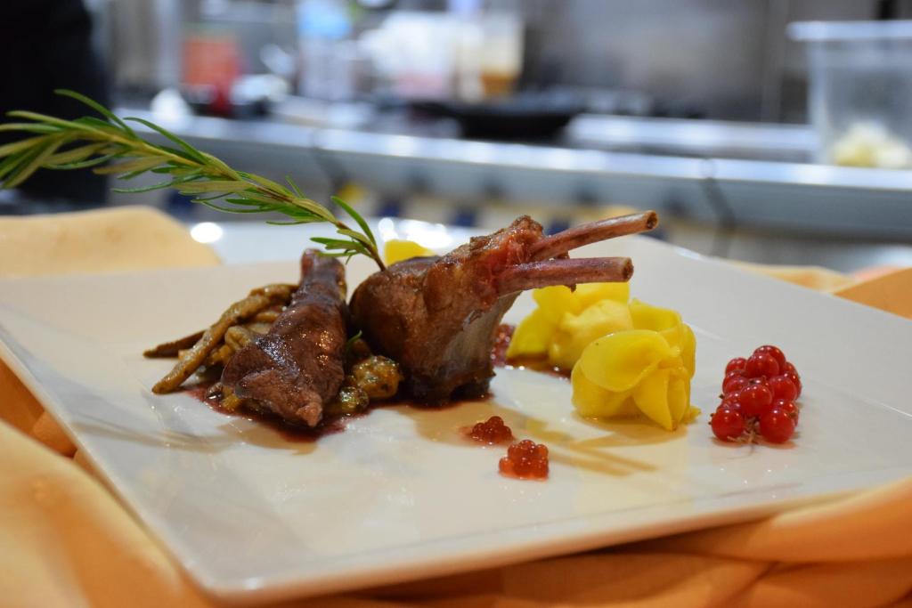 Grezns ēdiens ar jēra gaļu, kartupeļiem un ogām, dekorēts ar rozmarīnu. Ideāls piemērs elegantai restorāna maltītei.