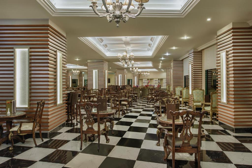 Eleganta restorāna iekārtojums viesnīcā Delphin Deluxe ar melnbaltu grīdu.