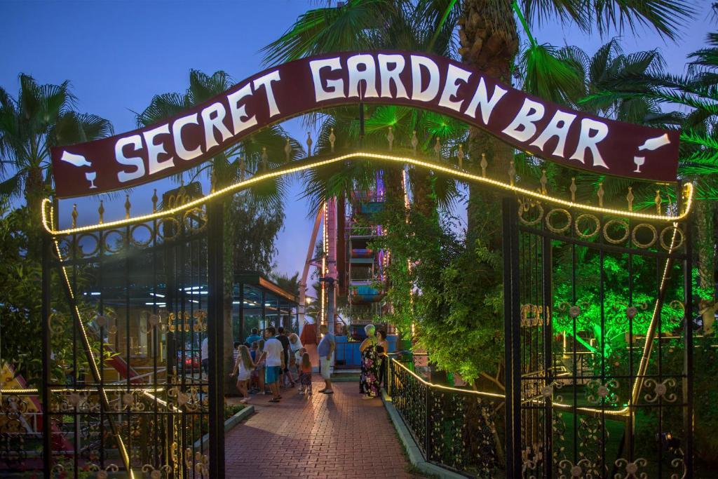 Ieeja uz Secret Garden Bar pie Delphin Deluxe viesnīcas ar palmām apkārt.