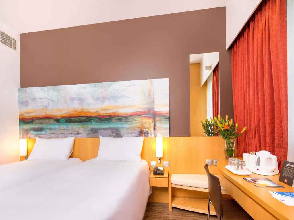 Ibis One Central Trade Center numurs ar divvietīgu gultu un mākslas darbu.