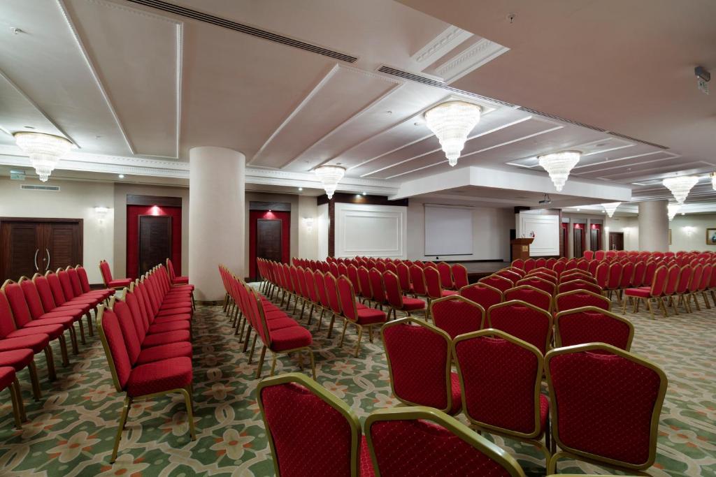Konferenču zāle Saphir Resort & Spa ar sarkaniem krēsliem un modernu apgaismojumu.