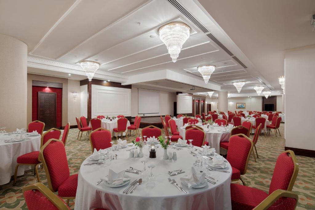 Eleganta svinību zāle Saphir Resort & Spa ar sarkanām krēslām un dekoratīvām lustrajām.